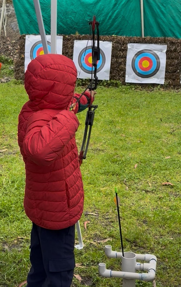 Scout aiming a bow and arrow at archery targets