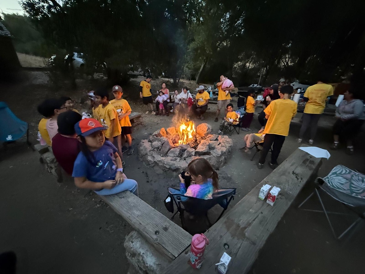 Pack 986 families gathered around a large campfire at dusk