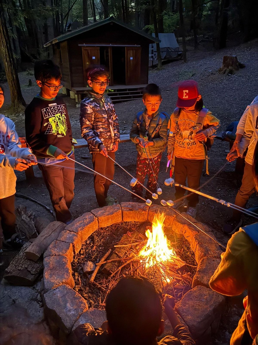 Scouts roasting marshmallows around a campfire at a Pack 986 campout