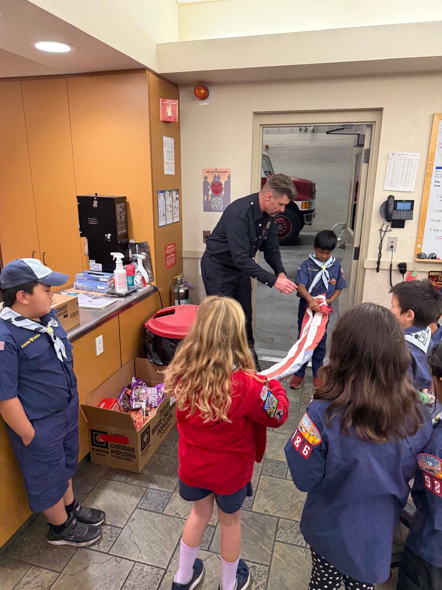 Firefighter teaching scouts to fold a flag during popcorn delivery