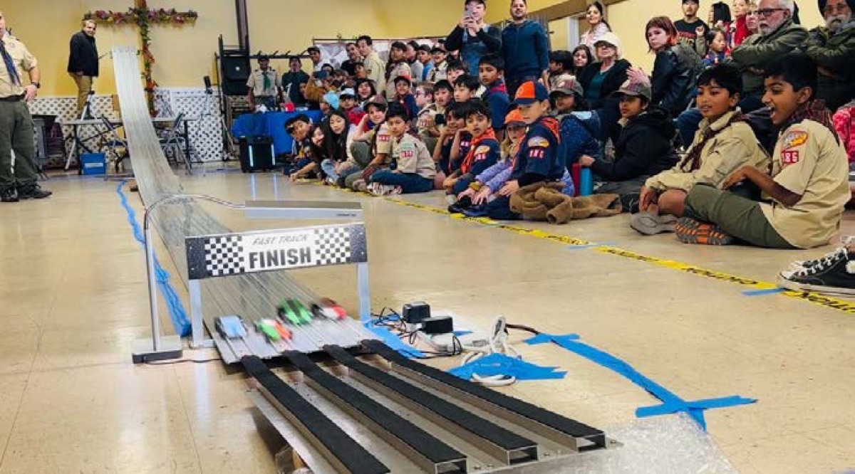 Crowd watching cars race at the Pack 986 Pinewood Derby